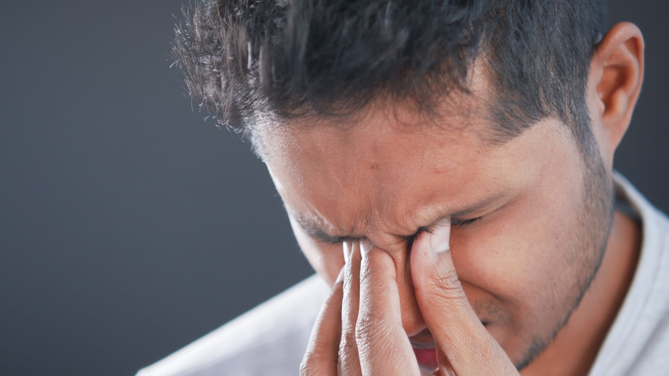 Close up of upset man suffering from strong eye pain.