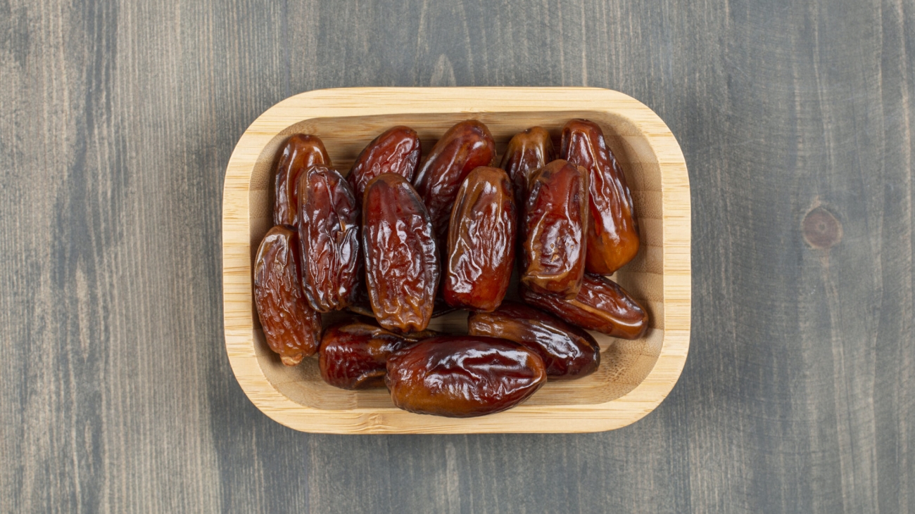 Juicy dates in a wooden plate on a wooden table . High quality photo